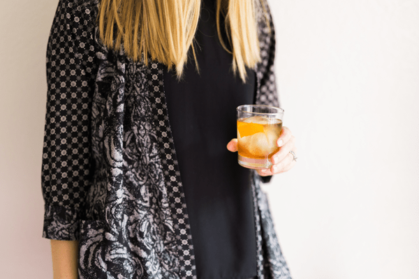 Woman holding a cocktail glass with an Old Fashioned.