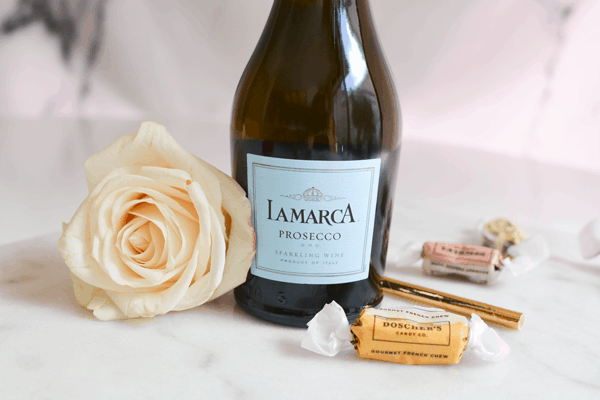 A small bottle of Prosecco with some caramel candies and a rose for a fun gift idea. 
