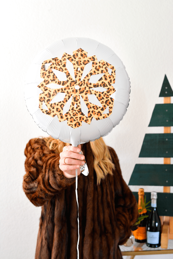 Woman holding snowflake balloon in front of her face. 