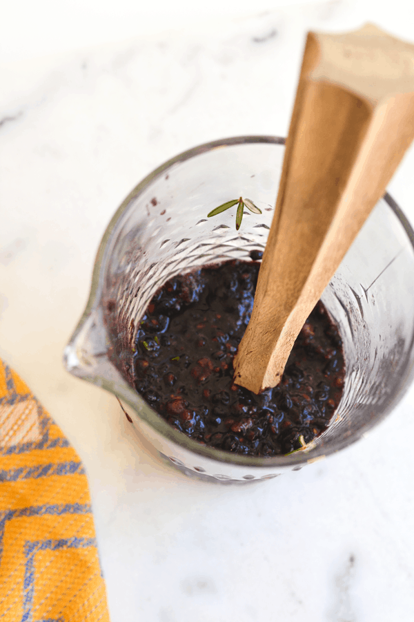 A bar pitcher with muddled fresh blackberry and some lemonade on a cutting board