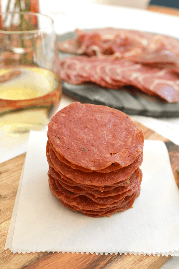 A stack of baked salami crisps on a piece of folded parchment paper.