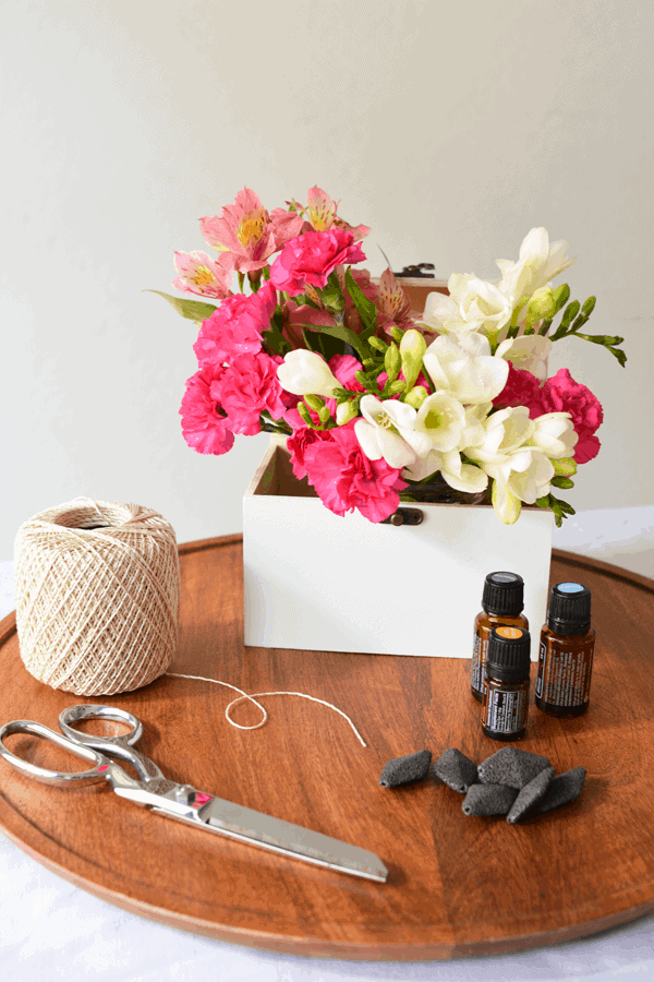 Supplies to make a DIY shower diffuser with lava rock next to bottles of essential oils.