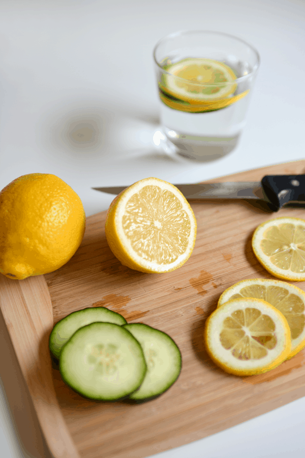 Lemon and cucumber slices on a cutting board to make DIY spa water by the glass.