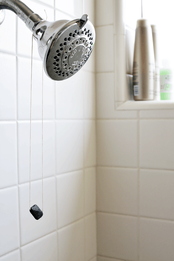 View of a shower head with a lava rock hanging off for essential oils.