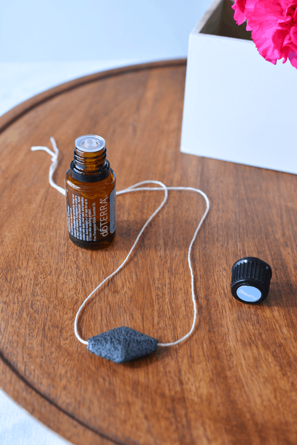 Image contains a lava rock shower diffuser and an open bottle of essential oils.

