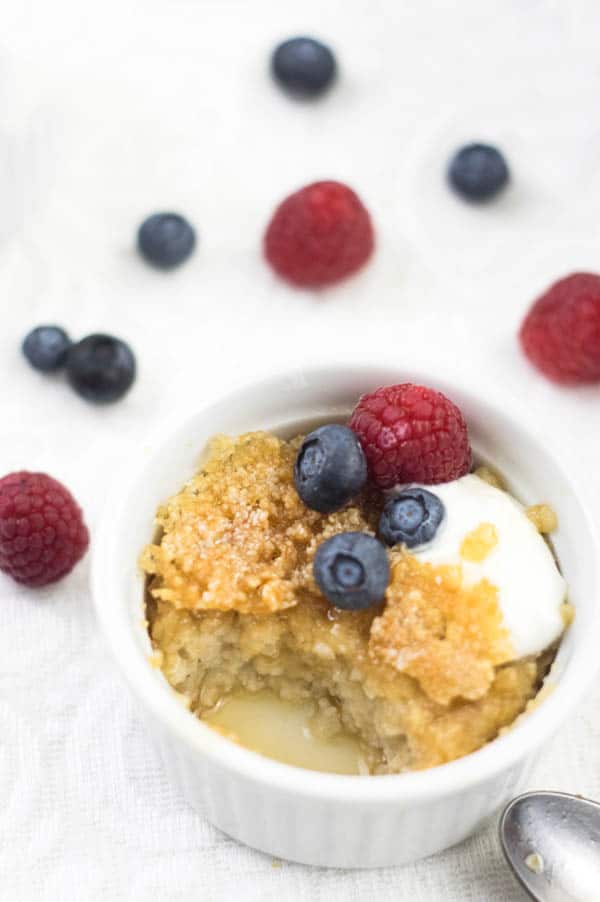 Oatmeal Brûlée topped with fresh berries and yogurt with a spoonful taken out of it.