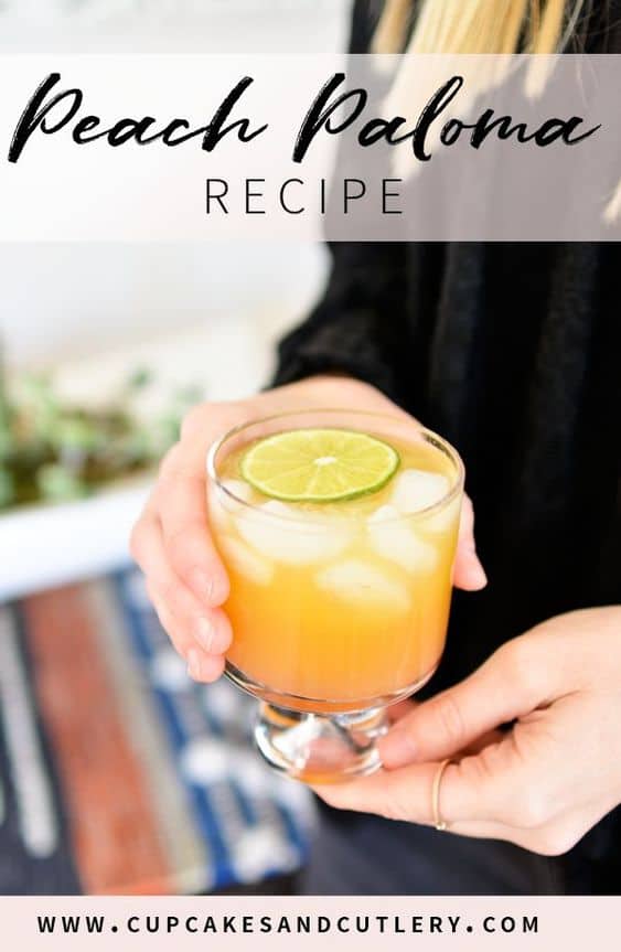 Woman in long sleeve black shirt holding a peach paloma cocktail.