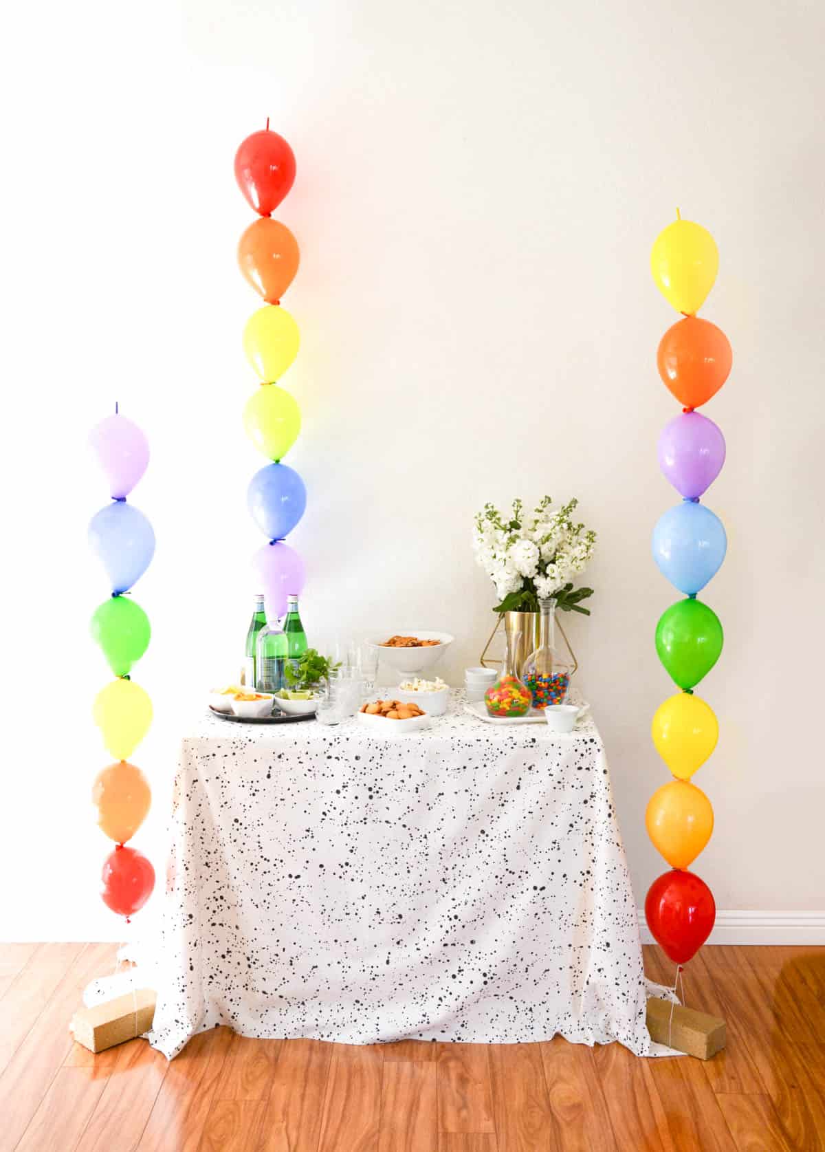 A St. Patrick's Day party table flanked by rainbow balloon columns.