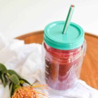 Close up of an insulated cup with a red smoothie.