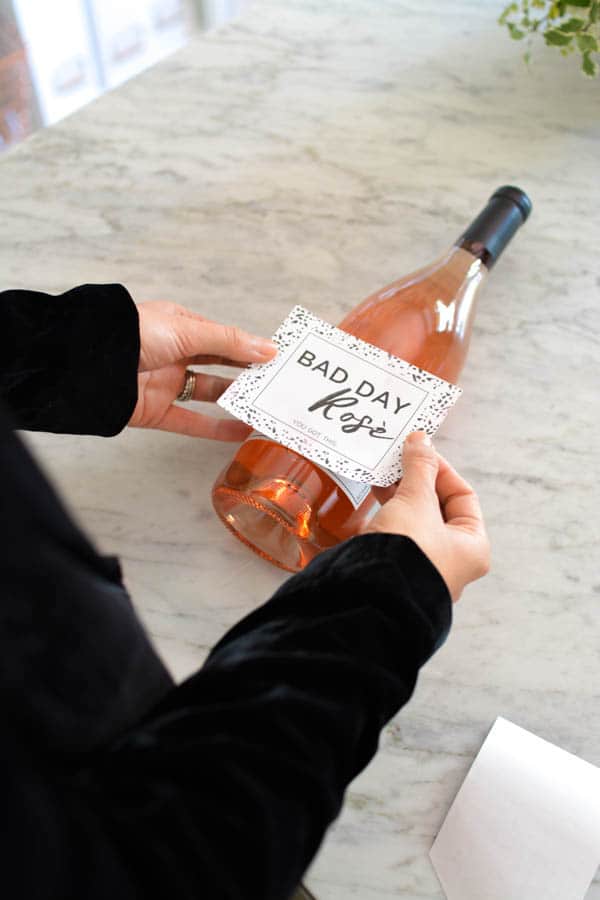 Woman putting a wine label sticker on a bottle of rose.