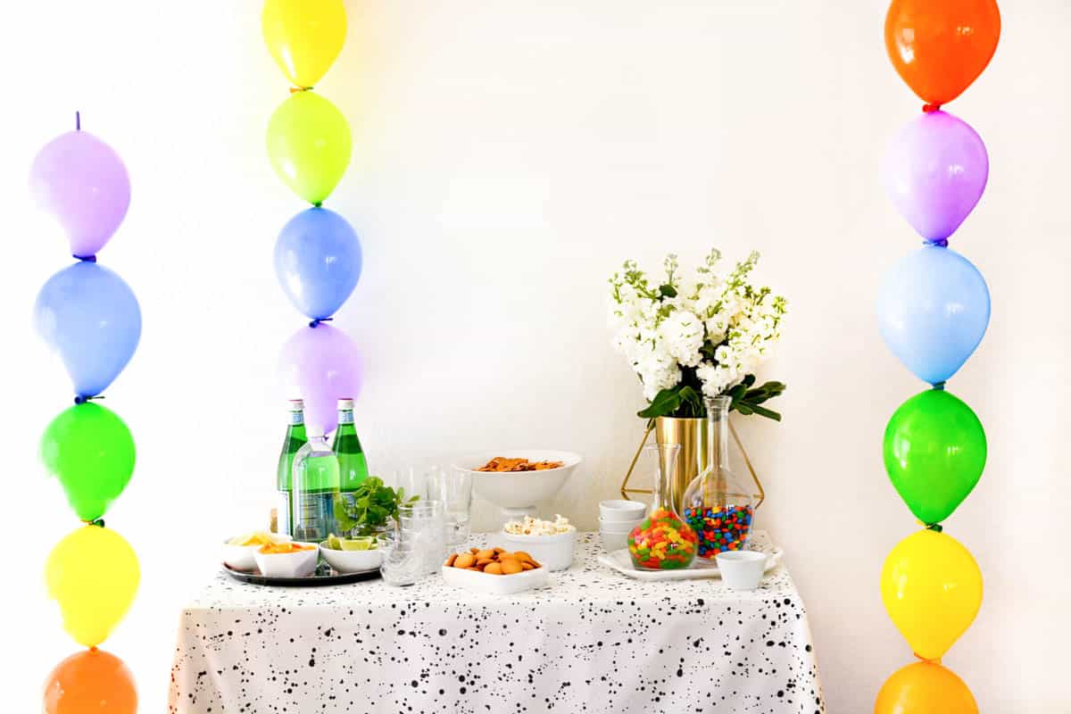 Linking rainbow balloons in a column next to a party table.