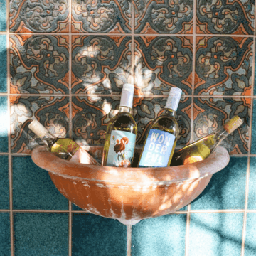 Wine bottles in a fountain on a wall.