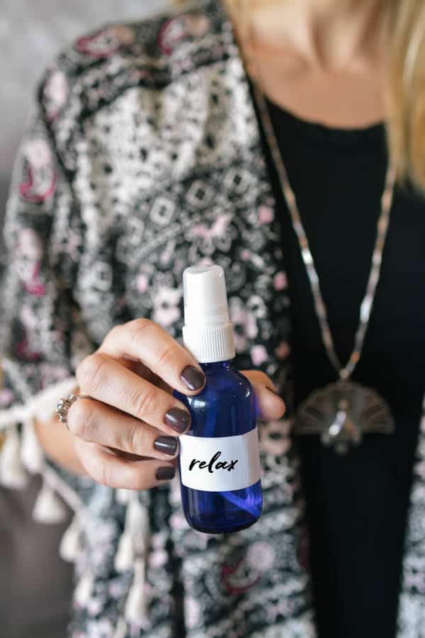 Woman holding a blue glass bottle with an essential oil room spray. 