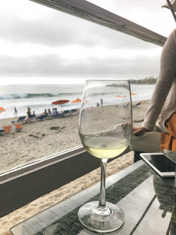 A glass of wine on a table with the ocean in the background for a moms trip weekend getaway. 