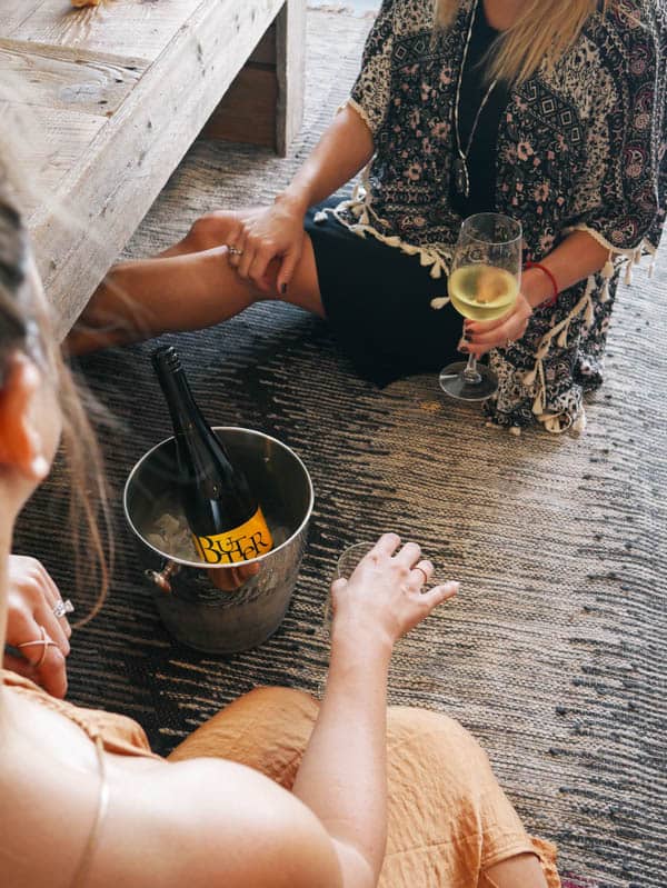 Women sitting on the floor enjoying a bottle of wine. 