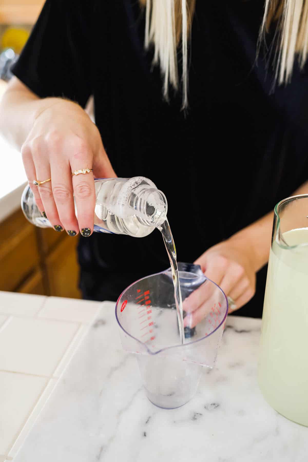 Woman measuring simple syrup for a large batch of margaritas.