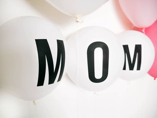 Close up of white balloons that say MOM.