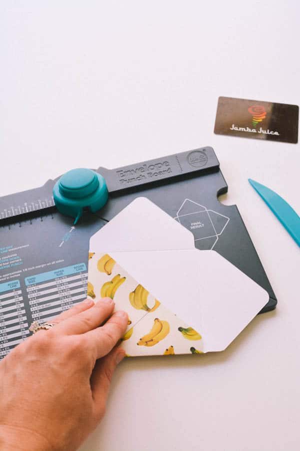 woman showing how to make a homemade paper envelope on top of the tool to punch out the paper