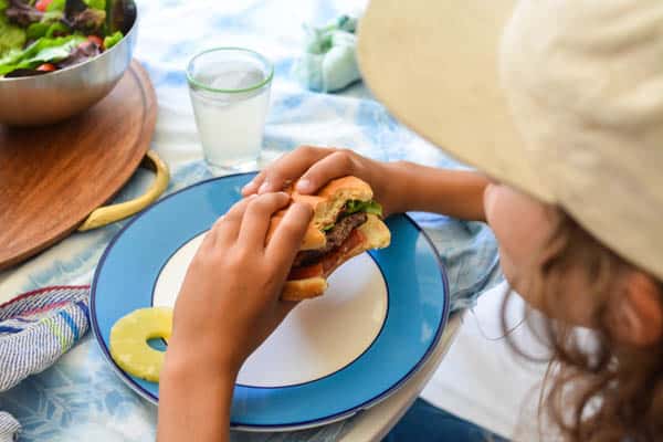 A kid eating a hamburger. 