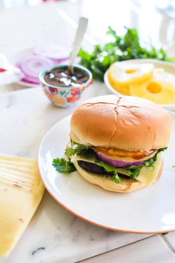 A BBQ pineapple burger on a plate on a counter. 