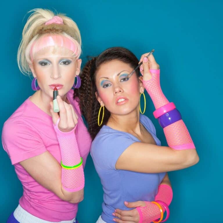 Close up of 2 women dressed in purple and pink 80's outfits.