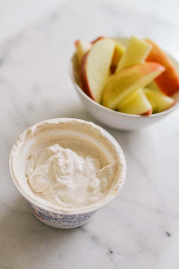 Easy Greek yogurt apple dip in the tub with a bowl of apple slices in the background.