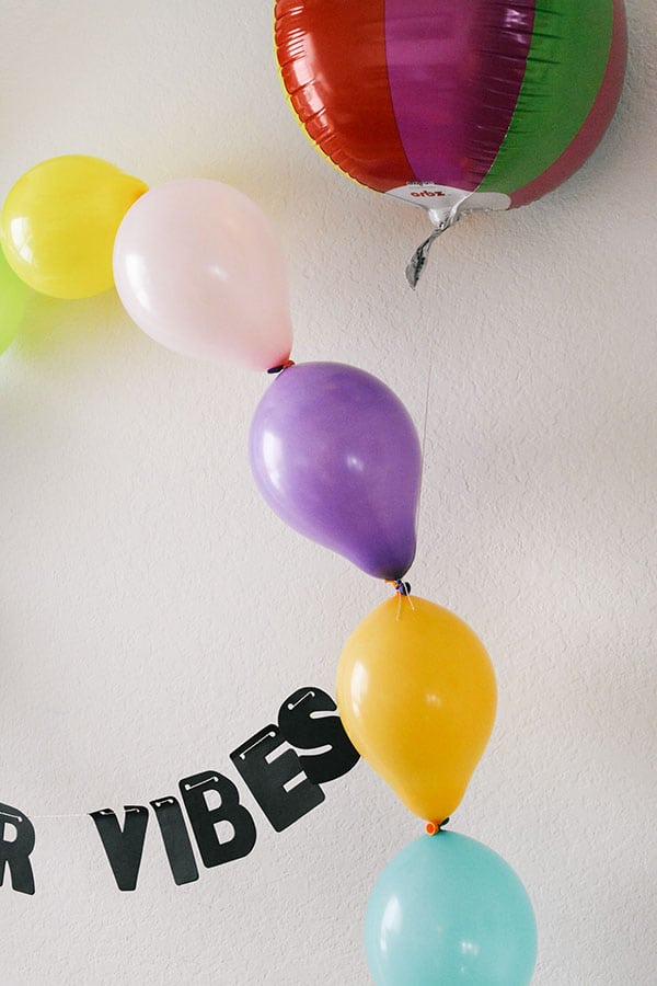 Close up image of a balloon arch with a summer vibes garland.