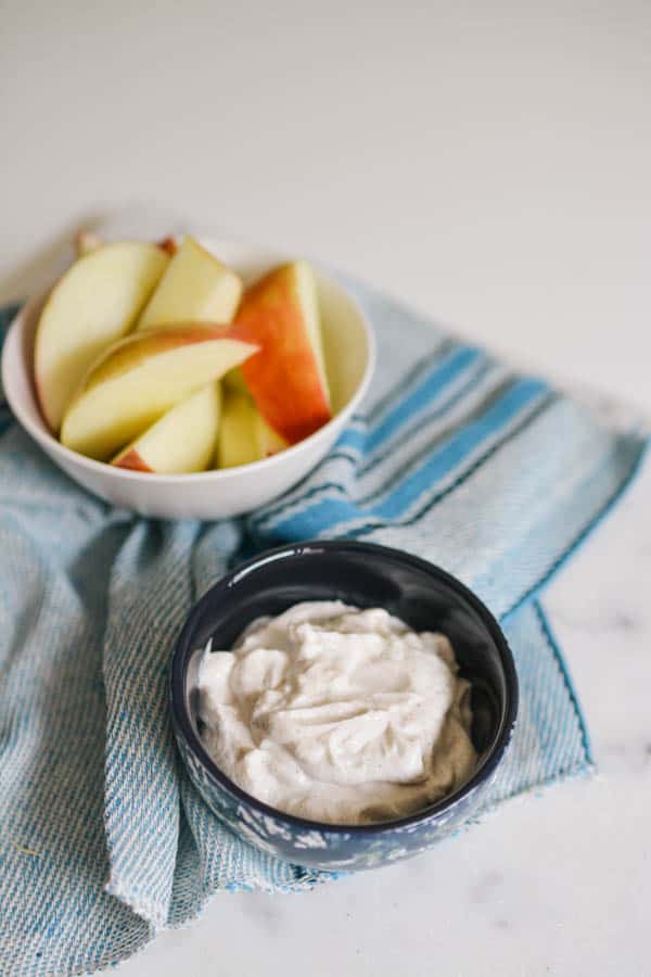 Greek yogurt healthy apple dip in a black bowl with apple wedges.
