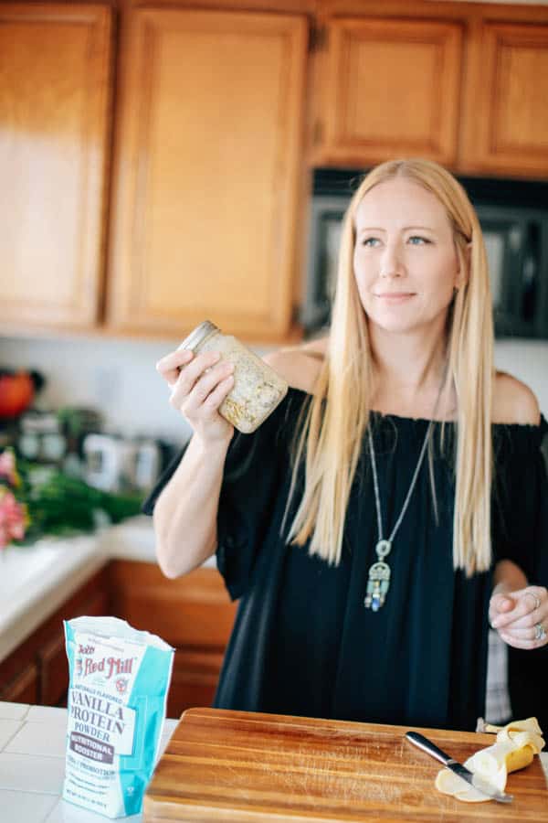 A woman shaking a mason jar full of overnight oats ingredients.