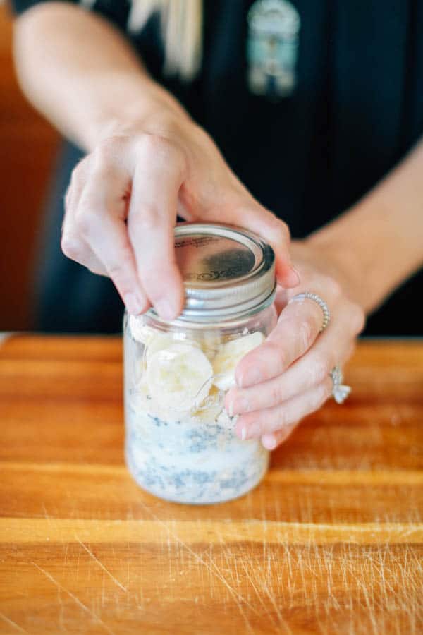 A woman tightening the lid to overnight oats in a jar.