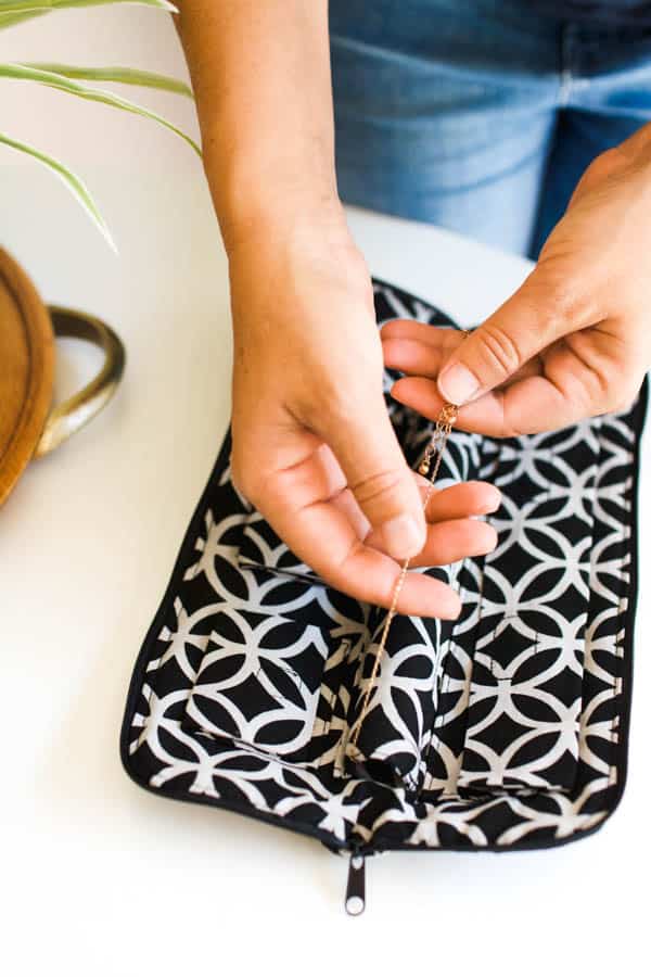 Woman using No Knot jewelry case to keep necklaces from tangling while packing for travel.