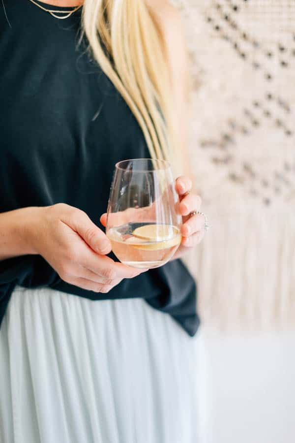 Woman holding a stemless wine glass with a white wine spritzer.