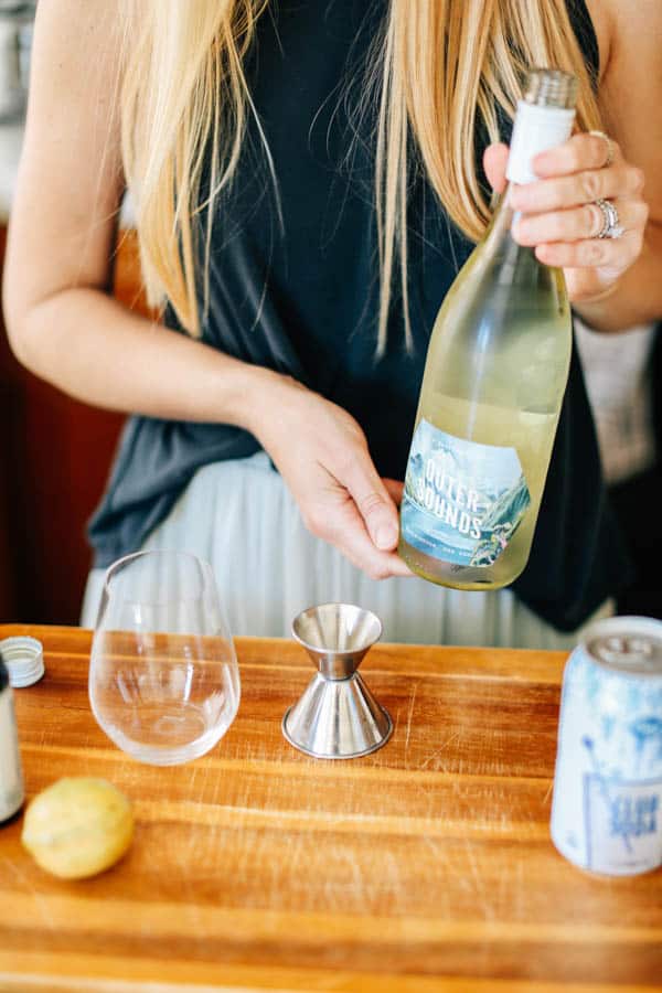 Woman holding a bottle of sauvignon blanc to make a wine spritzer with. 