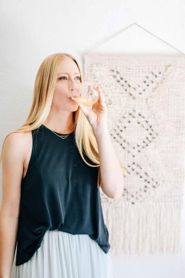 Woman sipping a white wine spritzer out of a stemless wine glass.