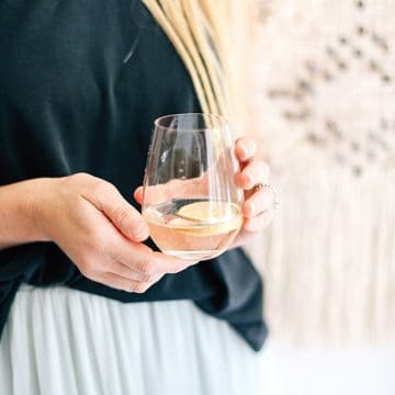 Close up of a woman holding a stemless wine glass in her hands.