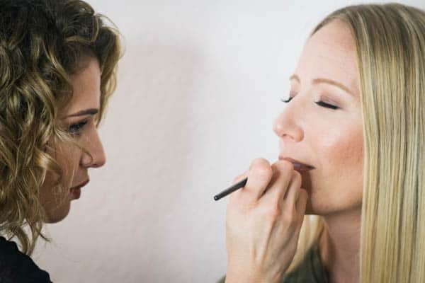Makeup artist putting on lipstick.