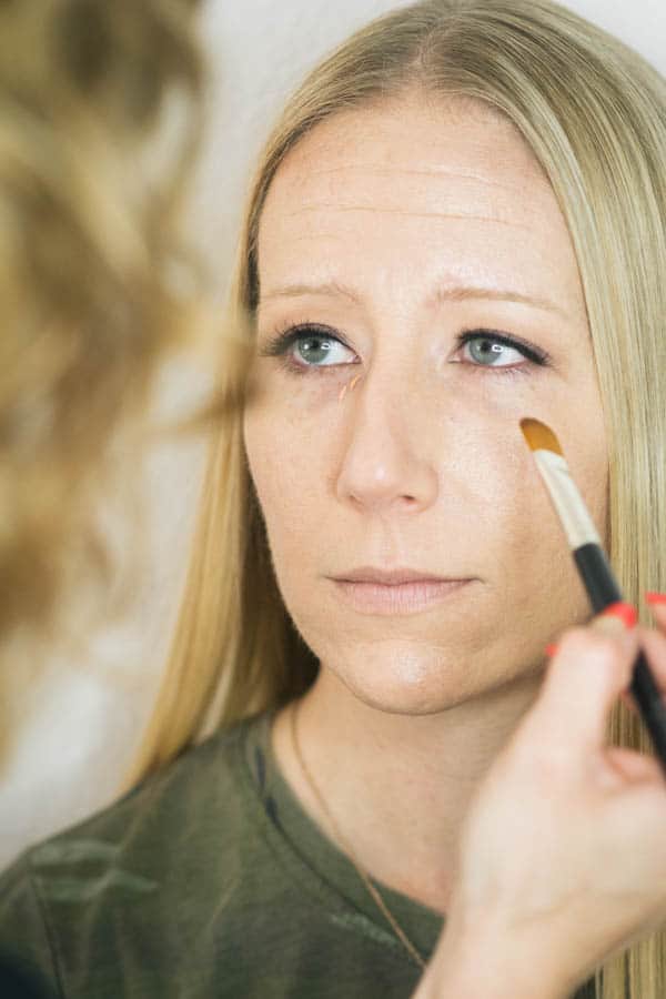 Makeup artist applying color corrector to the undereye area.