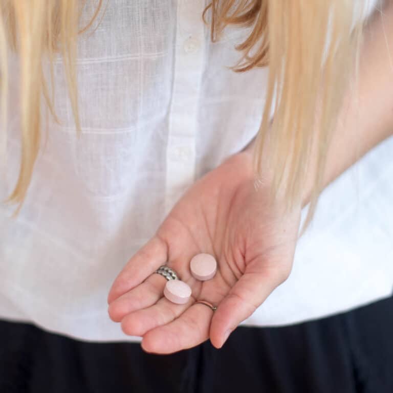 Close up of a woman's hand with two Zaca chewable tablets in it.