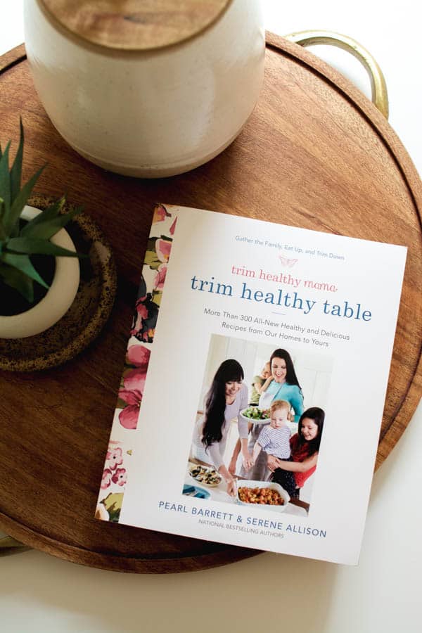 The cover of the Trim Healthy Mama Cookbook on a wooden tray.
