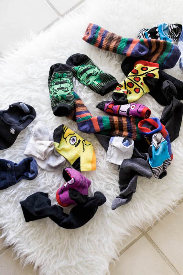 A pile of kid's socks on a white fluffy carpet. 
