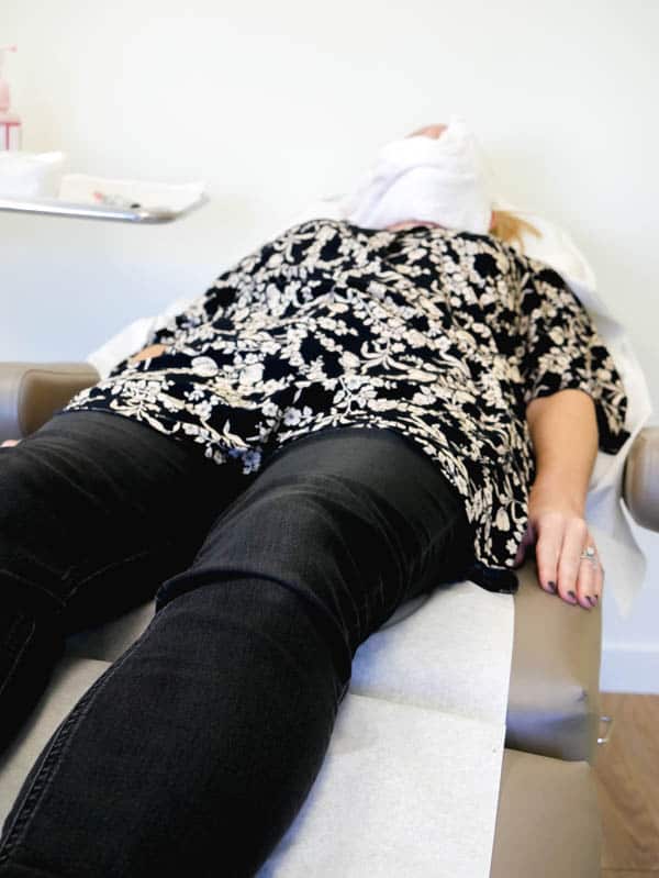 Woman laying on an exam table getting a microneedling facial treatment.