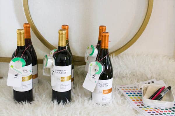Bottles of wine with name tags and Scotch tap hung around the neck for a holiday party favor. 