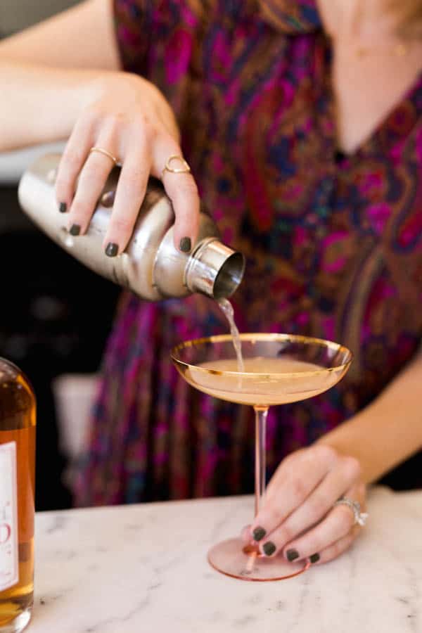 A spiced rum cocktail being poured into coupe glass.