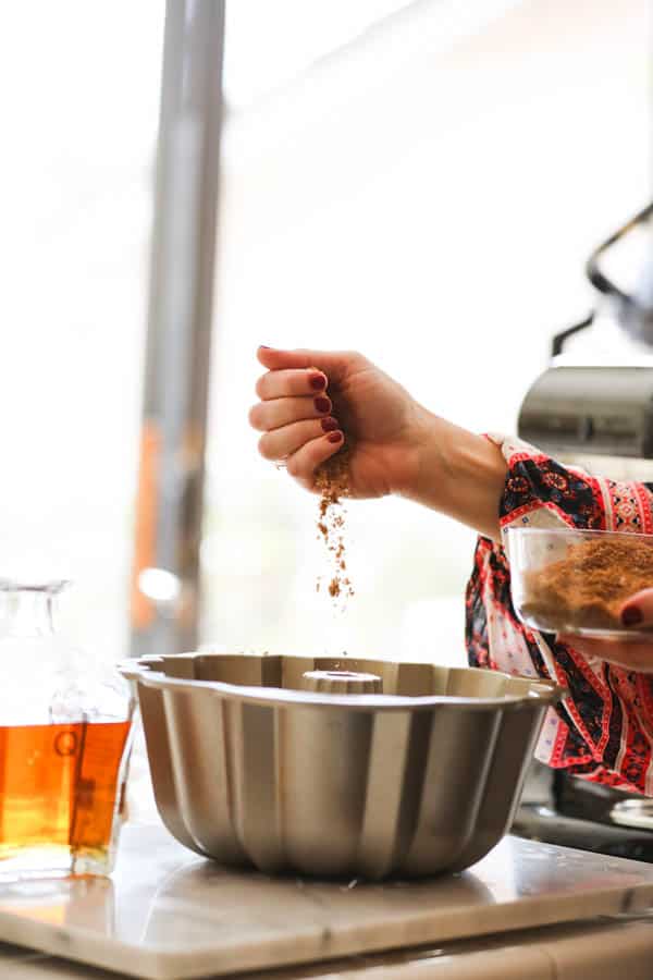 Woman sprinkling some brown sugar into a bundt pan.