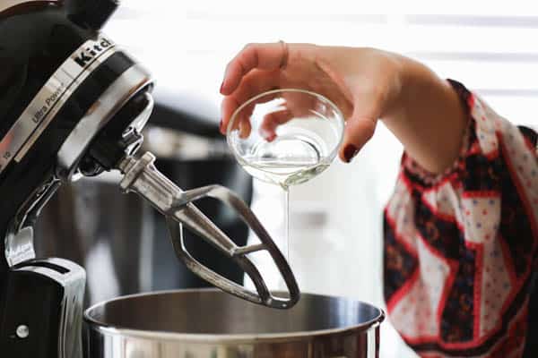 Woman pouring oil into a stand mixer.