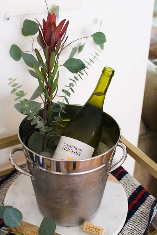 A silver wine bucket with a bottle of white wine and some fresh green leaves sticking out. 