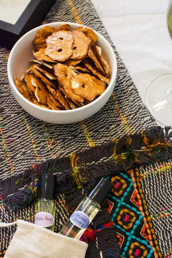 A bowl of pretzels on a table next to a few roller ball bottles with a "stress away" label on them. 