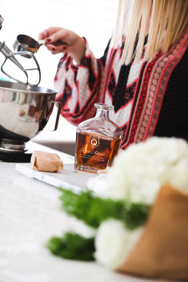 Woman adding spiced rum to a stand mixer.