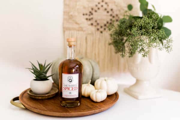 A bottle of Don Q spiced rum on a table with pumpkins.