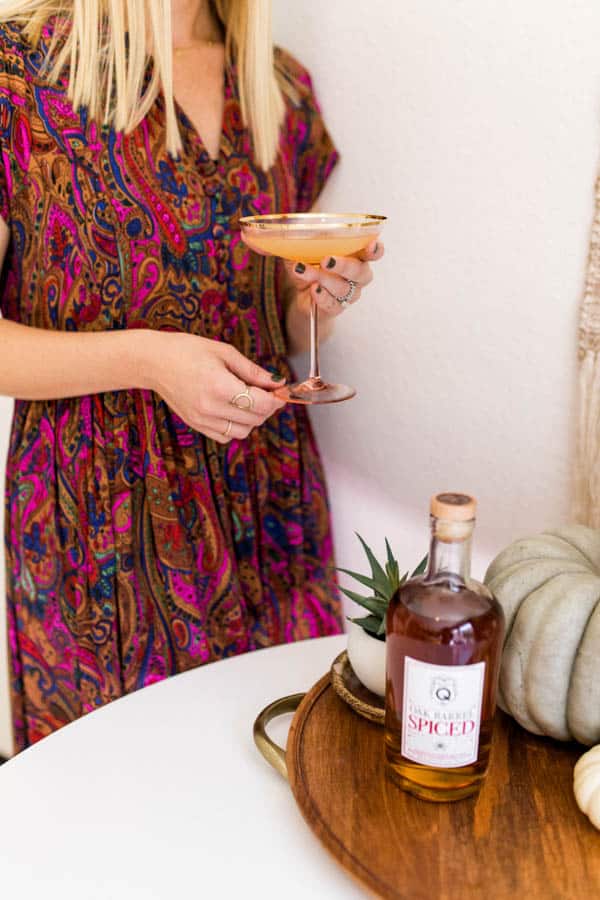 Woman holding a coupe cocktail glass with a spiced rum daiquiri.